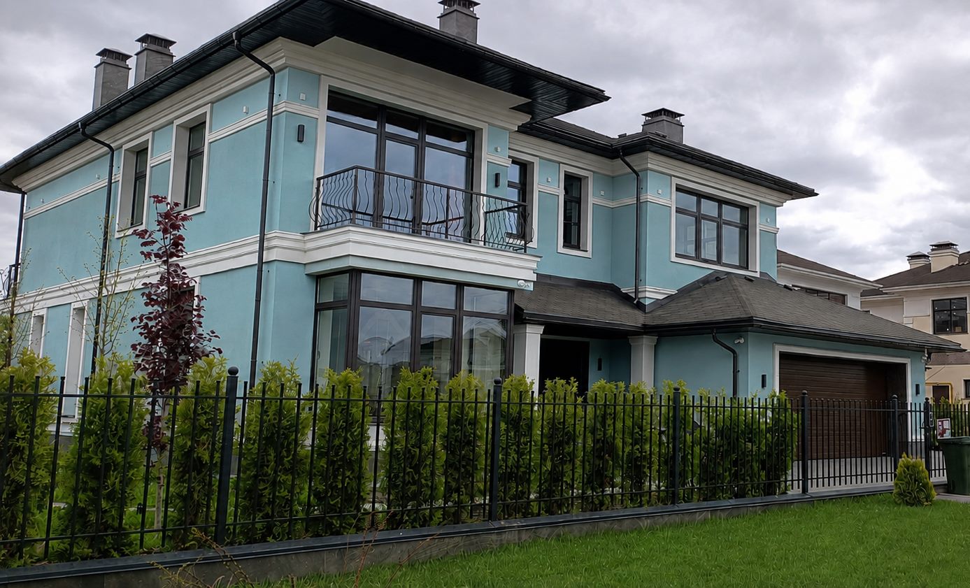 The house from the street — two floors with large glazed openings on both, blinds behind the glass