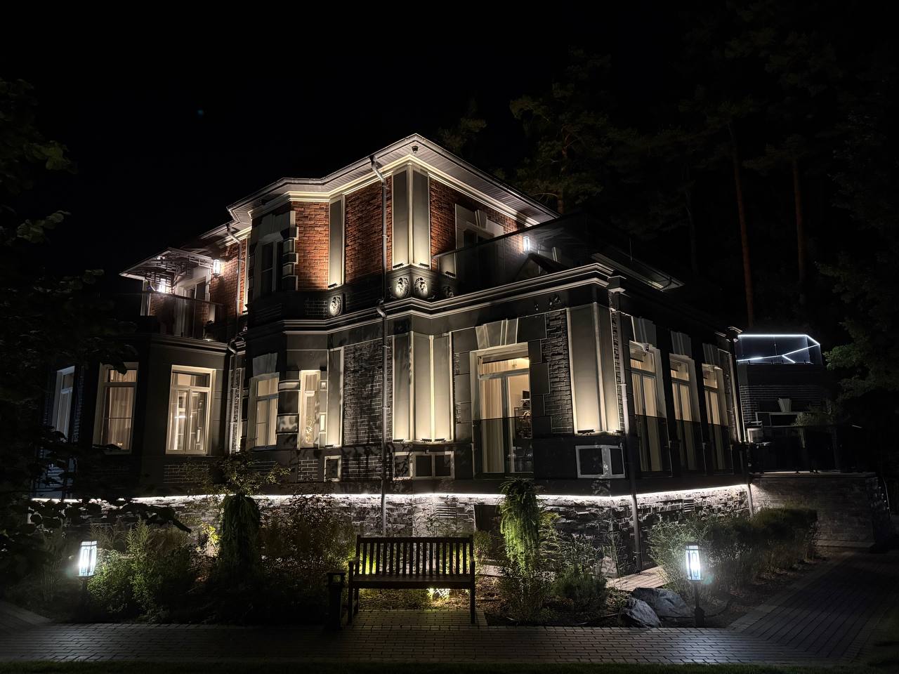 The residence at night — facade uplighting, LED lines along the cornices and lit garden paths